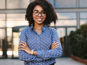 Business professional standing confidently with office building in background.