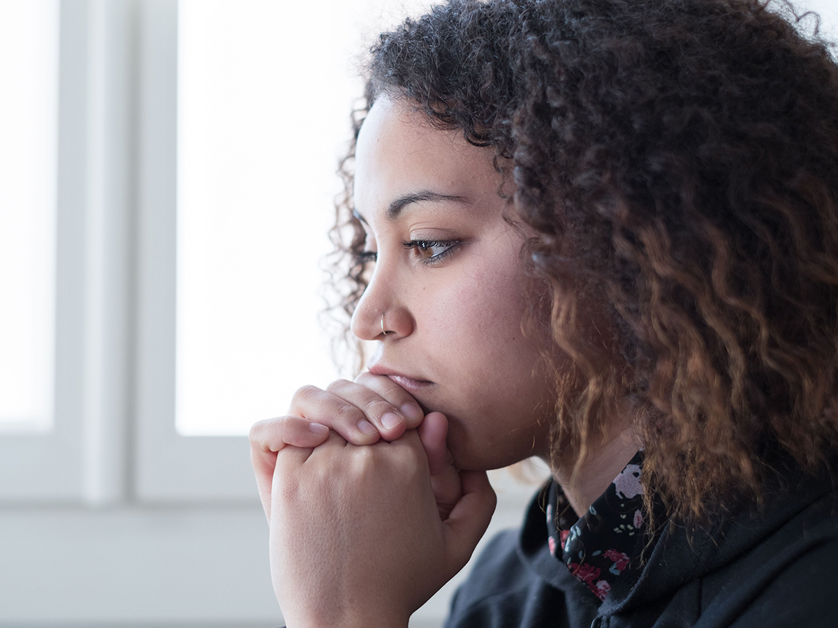 Image of a woman thinking while resting her hands under her chin.